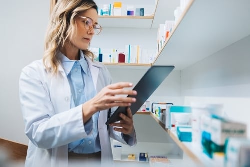 Eine Apothekerin entnimmt Medikamente aus einem Schrank.